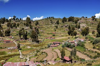 Terraced fields and farm houses stretch across green hills under blue skies, the countryside and