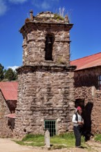 Stony church tower with red roof and a man wearing traditional clothes next to it, The knitting men
