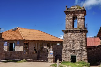 A historic stone building with a bell tower and red tile roofs against a blue sky, The historic