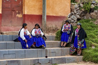 Group of woman in traditional dress sitting on stairs and talking, The woman on Taquile Island in