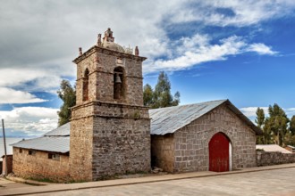 Stone church building with red gate and bell tower under changing skies, The historic church on