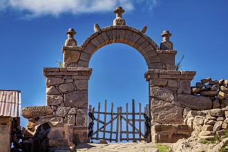 Massive stone archway with decorated sculptures rising into a clear blue sky, stone gates on