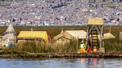 Small village of reed huts with people on the shore in front of an extensive urban landscape, The