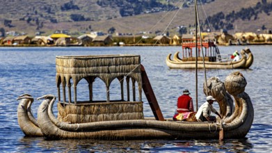 Traditional reed boat with people on a calm lake in front of a shore with reed huts, The floating