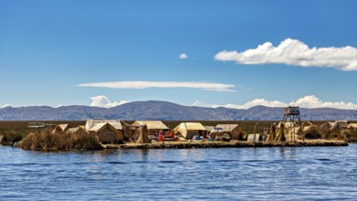 Reed huts on an island in the lake under a clear sky with mountains in the background, The floating