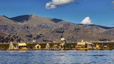 Small reed settlement on a lake against a mountain backdrop under a cloudy sky, The floating reed