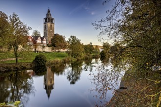 Church on the river, surrounded by autumnal trees with beautiful reflections in calm water, The
