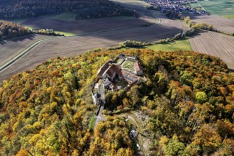 Aerial view of a castle on a hill surrounded by autumnal forest with colorful trees, Gleichenstein