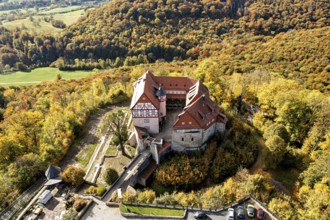 Historic castle surrounded by autumnal forest in a beautiful landscape taken from the air,