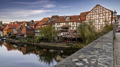 Historic half-timbered houses and beer garden along a river with a bridge at dusk, The town of Bad