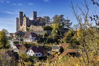 Medieval castle above a village with autumn trees under a blue sky, Hanstein Castle near Bornhagen