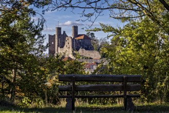 Bench in the foreground, medieval castle surrounded by trees, autumnal atmosphere, Hanstein Castle