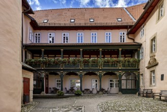 A quiet courtyard with historic half-timbered elements, balconies and decorative flowers under a
