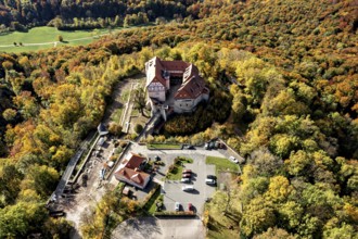 Castle taken from the air in the midst of autumn nature, with adjacent parking facilities,