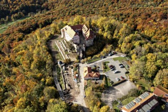 Aerial view of a castle in the autumn landscape with adjacent parking lot, surrounded by colorful
