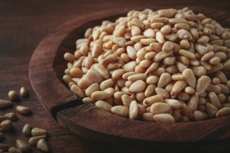 Peeled pine nuts, in a wooden bowl, on a wooden table, close-up, no people