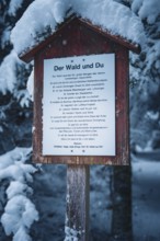 A snowy wooden sign in the forest against the backdrop of snow-covered trees, Broom Field, Black