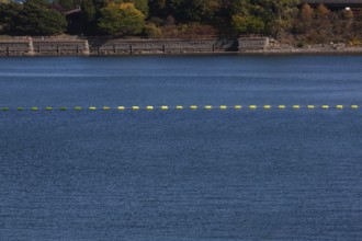 String of yellow cautionary navigation marker buoys on water surafce of river serving to warn,