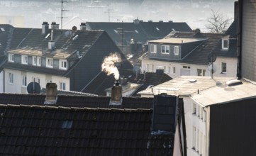 Smoke plume from a chimney over densely built residential area in the evening light, wintry city