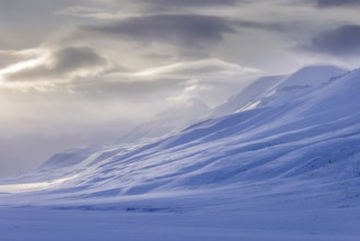 Snow covered mountain peaks along Adventdalen, Advent Valley near Longyearbyen at sunset in spring,