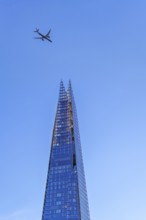 Airplane of British Airways flying over The Shard, skyscraper and tallest building in the United