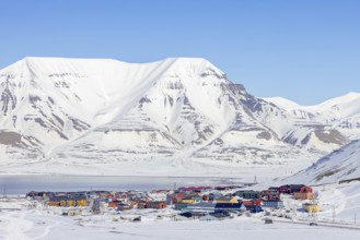 View over the town Longyearbyen on the shore of Adventfjorden and snow covered mountains in winter