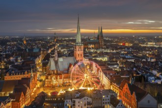 St. James' Church / Jakobikirche and illuminated Ferris wheel at evening Christmas market in winter