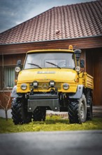Yellow Unimog with four-wheel drive on a lawn in front of a wooden house, tree work, Gechingen,