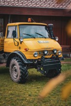 A yellow Unimog stands in the rain on a farm, tree work, Gechingen, Calw district, Germany