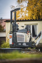 Small excavator in a courtyard next to a building in autumn, tree work, Gechingen, Calw district,