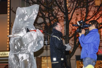 Ice carving artist in front of his ice sculpture interviewed by a GEA reporter during ice carving