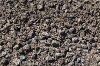 Close-up of sand mixed with grey crushed stone aggregate used to form a bed for constructing roads