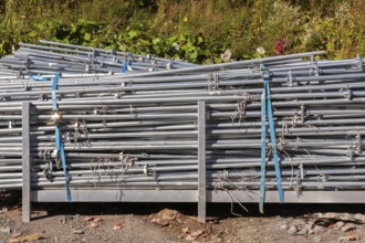 Pile of stacked heavy duty galvanized steel poles in outdoor storage yard in early autumn, Quebec,