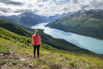 Female mountaineer enjoying views of blue lake and mountains on Twin Peaks Trail, Eklutna Lake,
