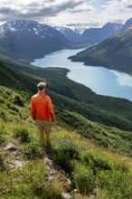 Mountaineer enjoys views of blue lake and mountains on Twin Peaks Trail, Eklutna Lake, Chugach