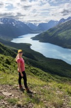 Female mountaineer enjoying views of blue lake and mountains on Twin Peaks Trail, Eklutna Lake,