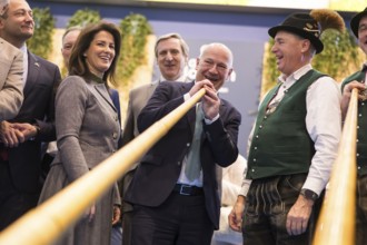 Kai Wegner (Governing Mayor of Berlin) tries out an alphorn at the Bavarian stand during the