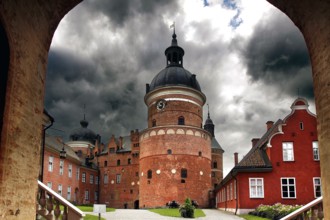 Gripsholm Castle in Mariefred through an archway with a heavily cloudy sky, Mariefred,