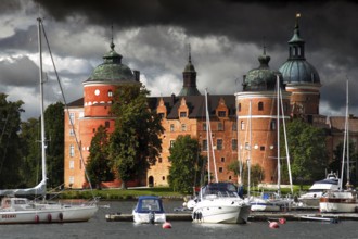 Gripsholm Castle in Mariefred against a cloudy sky with adjacent boats, Mariefred, Södermanland,