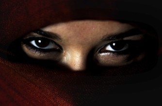 Mysterious eyes peek out from under a red veil