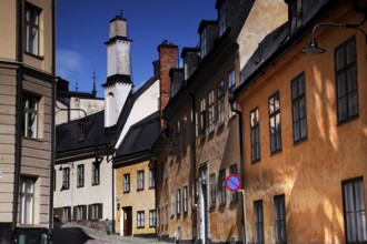 Colourful old town houses in Södermalm, Stockholm, with a church tower in the background,