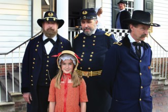 Soldiers in historic uniforms with a girl on the street in Colonial Williamsburg, Williamsburg,