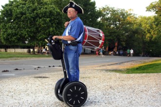 Man in period clothing rides on Segway and carries a drum, a rare sight, Williamsburg, Virginia,