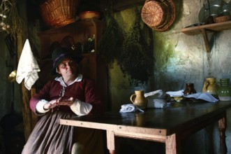 Woman wearing historical costume in a rustic house at Plimoth Plantation, Plymouth, Massachusetts,