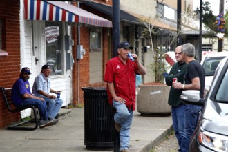 Men in casual clothes talk outside Fred's Lounge in Mamou, Mamou, Louisiana, USA