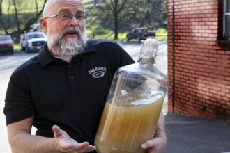 An employee from Jack Daniel's Distillery shows a large glass container, Lynchburg, Tennessee, USA