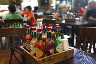 Different Tabasco bottles in the foreground of a restaurant, Avery Island, Louisiana, USA