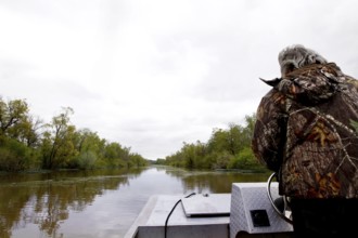 Person in a boat traveling on a calm river through a swamp, Atchafalaya Basin, Louisiana, USA