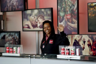 An employee of the Coca-Cola Museum in Atlanta, surrounded by cola cans and photographs, Atlanta,