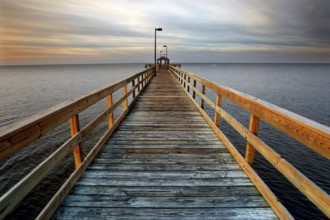 A long wooden pier stretches out into the calm sea at sunset in Biloxi, Biloxi, Mississippi, USA